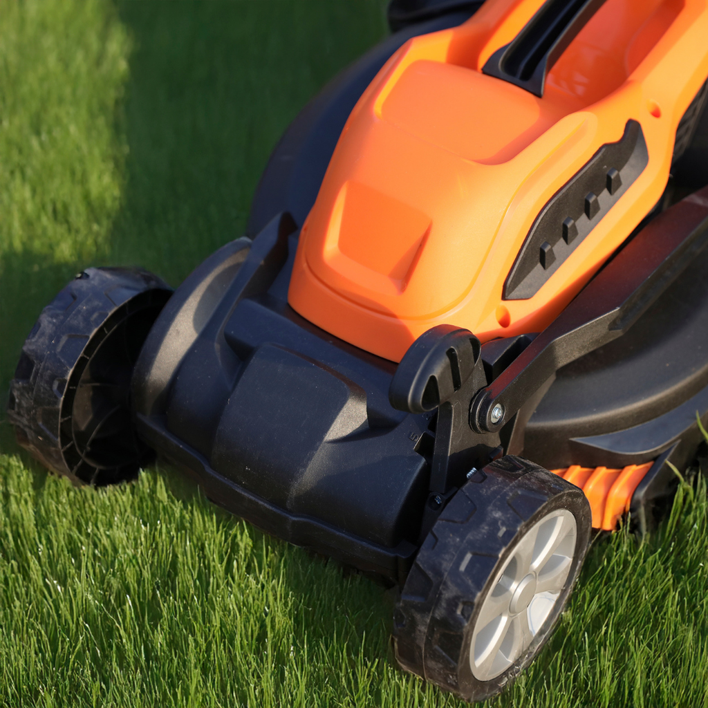 Close-up of an orange and black Yard Force EM U32 electric lawn mower on grass